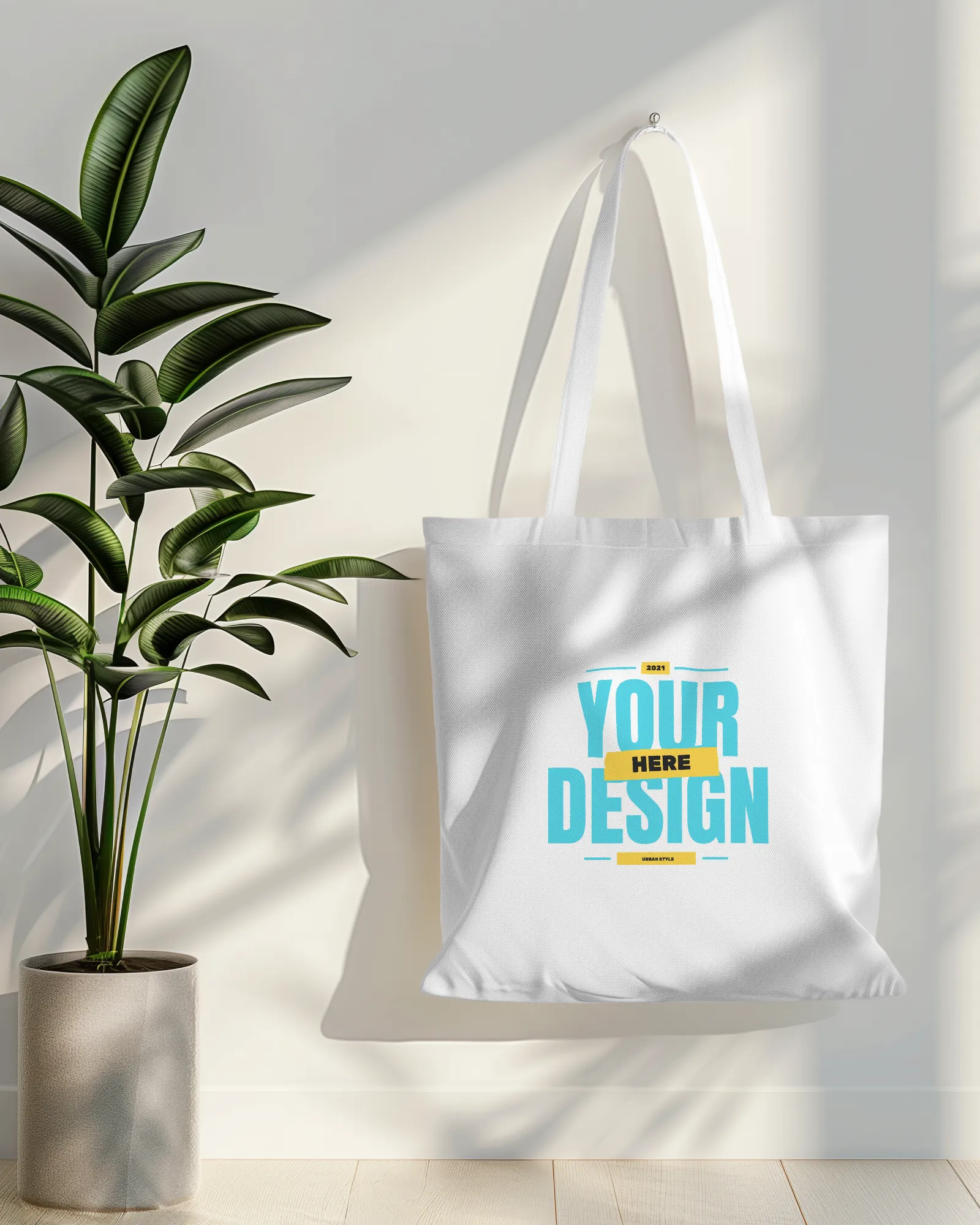 tote bag mockup hanging on white wall with plant in side
