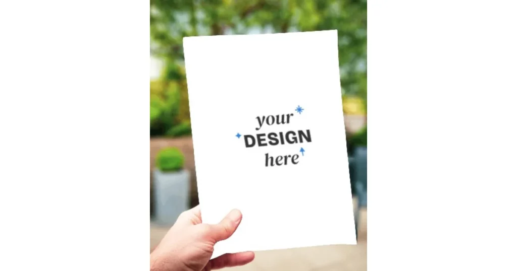 hand holding a flyer mockup with a garden in the background while holding the flyer