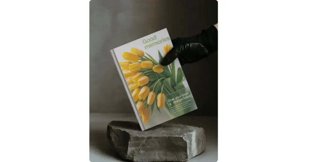 a4 book held by black-gloved hand on stone slab